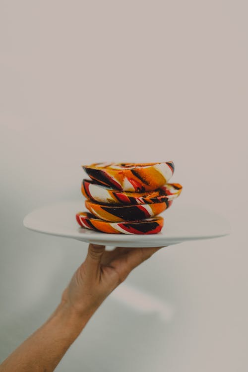 Person Holding a Ceramic Plate with Colorful Bread
