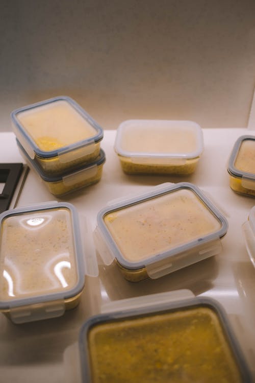 From above of delicious dishes in plastic containers placed on table in kitchen