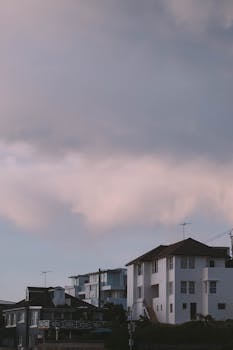 From below of cloudy sundown sky over residential district with various houses and buildings