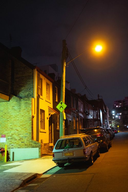 Free Various cars parked on narrow asphalt road near old residential buildings under cloudless night sky Stock Photo
