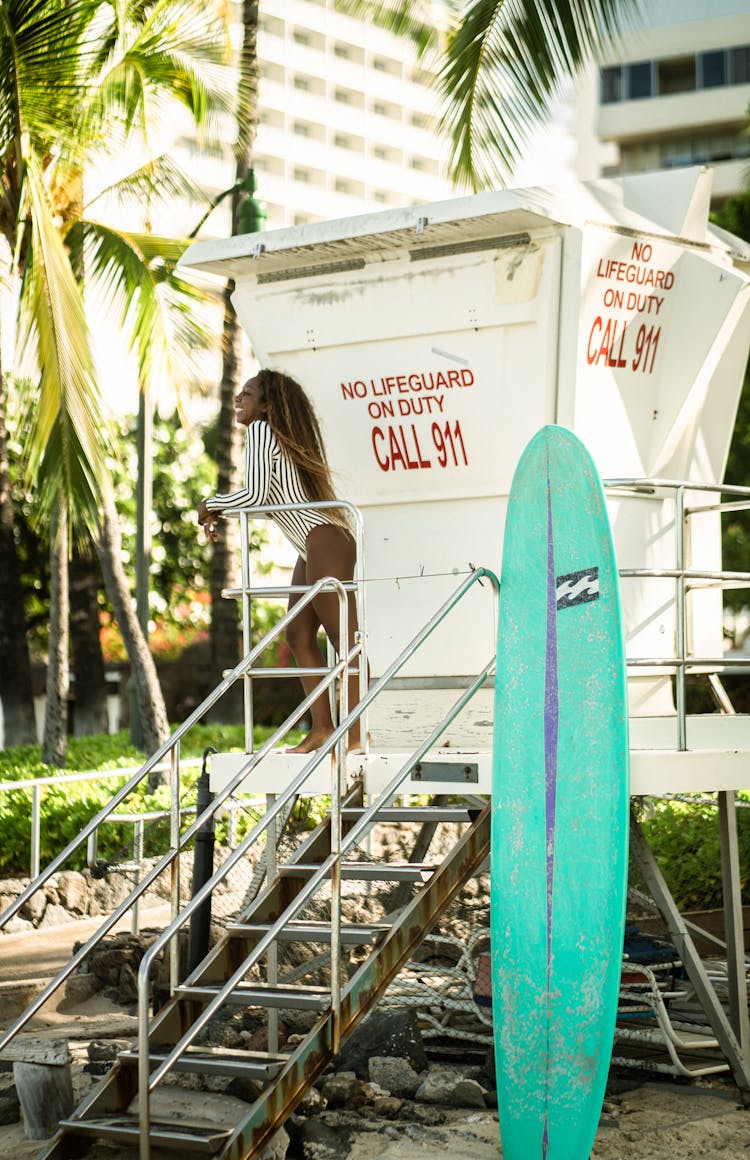 Cheerful Black Woman In Swimwear Standing On Lifeguard House Stairs