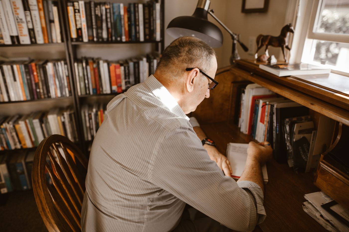 Man writing at a wooden desk