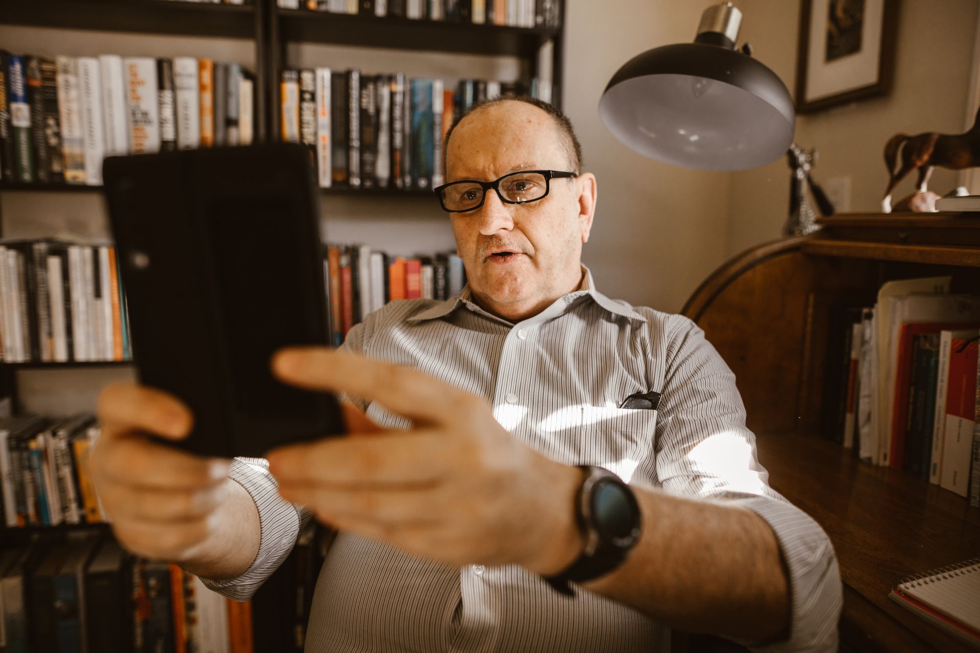 Elderly man with eyeglasses having a video call at home using a digital tablet.