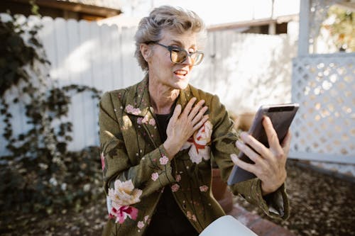 Frau Im Grünen Und Rosa Blumenmantel, Der Schwarzen Tablet Computer Hält