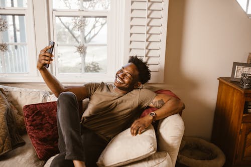 Happy Man Sitting on Couch while Having a Video Call 