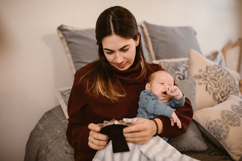 Free Mother Holding Her Baby while Looking at a Picture Frame  Stock Photo
