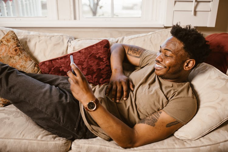 Man Lying On The Couch While Using His Smartphone