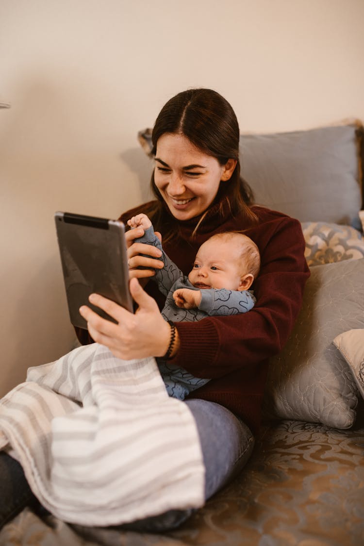 Mother Holding Her Baby While Having A Video Call Using A Tablet