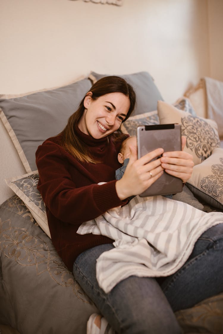 Mother Holding Her Baby While Having A Video Call Using A Tablet