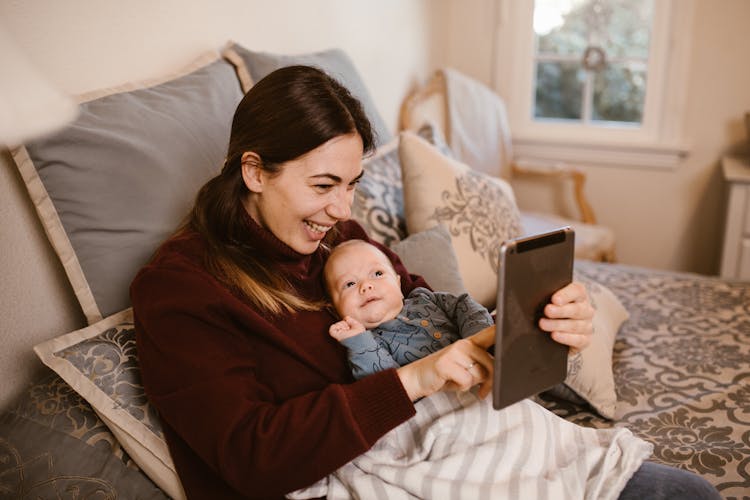 Mother Holding Her Baby While Having A Video Call Using A Tablet