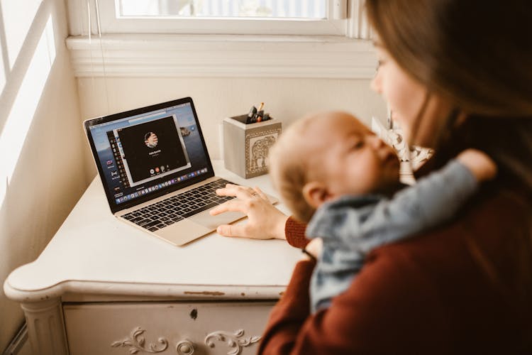 Mother Carrying Her Baby While Calling Her Husband On Laptop