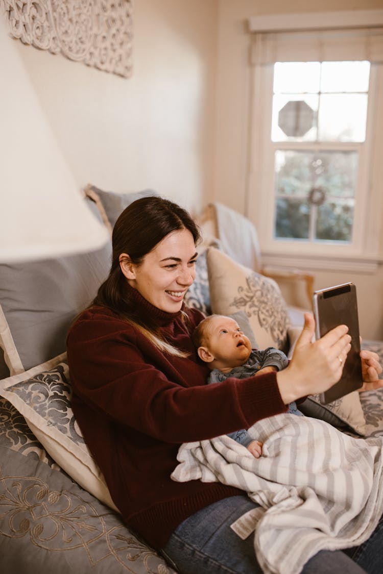 Mother Holding Her Baby While Having A Video Call Using A Tablet