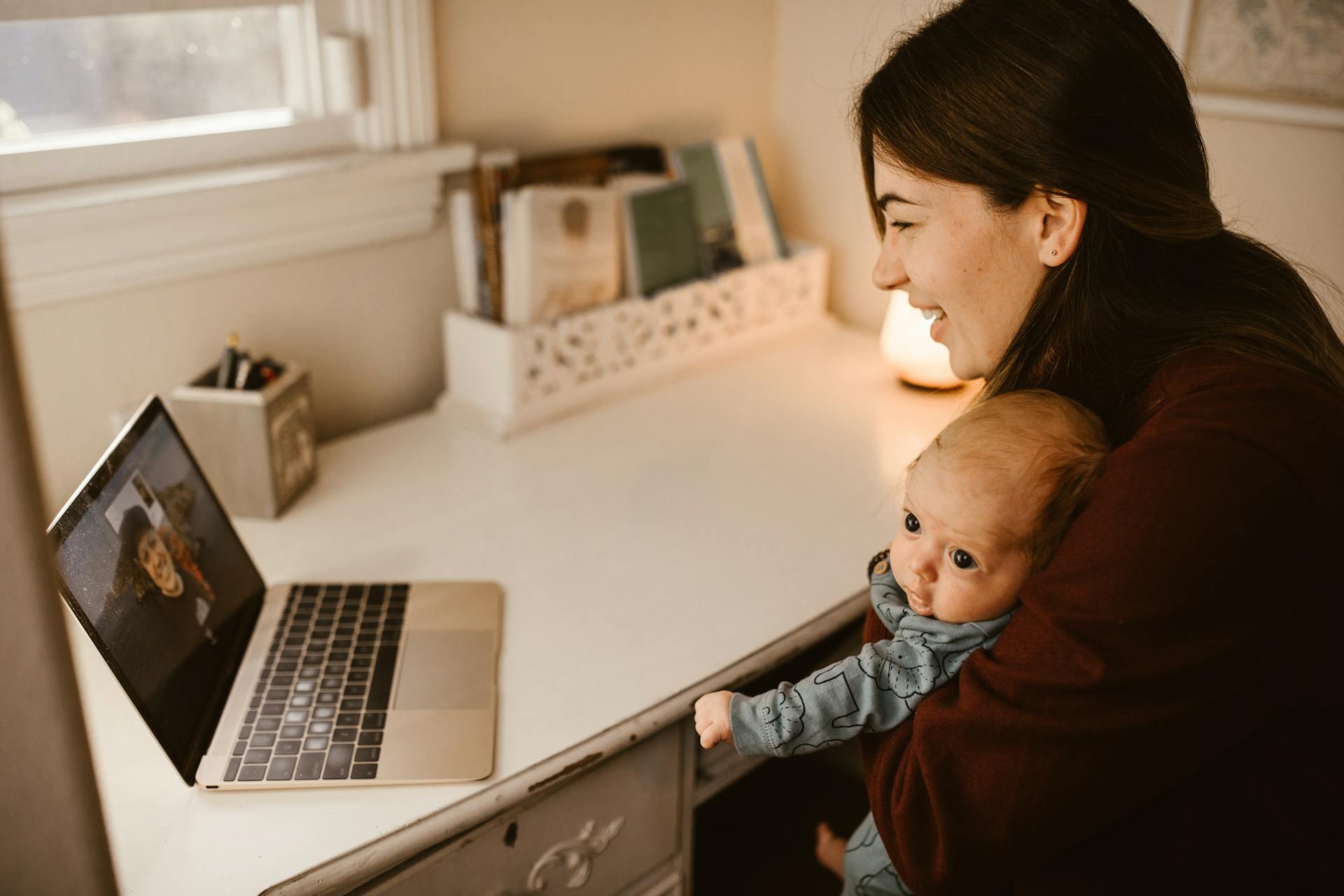 Mother Holding Her Baby while Having a Video Call Using a Laptop