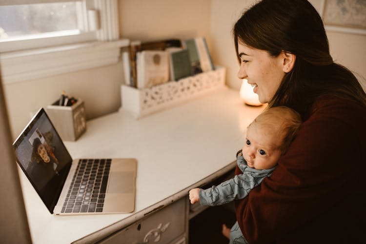 Mother Holding Her Baby While Having A Video Call Using A Laptop