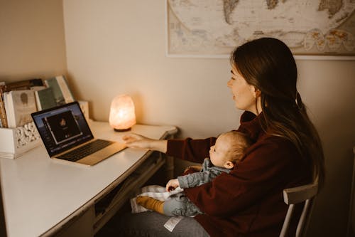Mother Holding Her Baby while Having a Video Call Using a Laptop