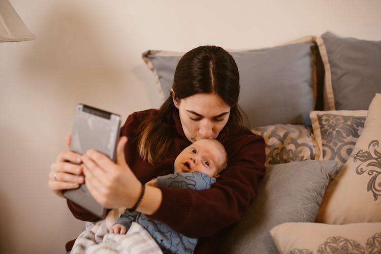 Mother Kissing Her Baby While Having Video Call