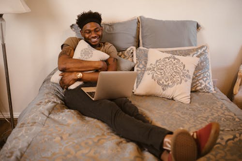 Man Sitting on Bed while Having Video Call on Laptop
