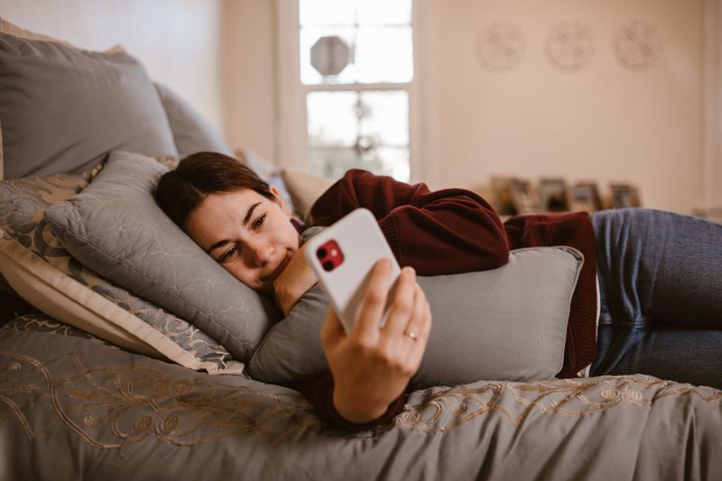 Woman looking at smartphone in bed