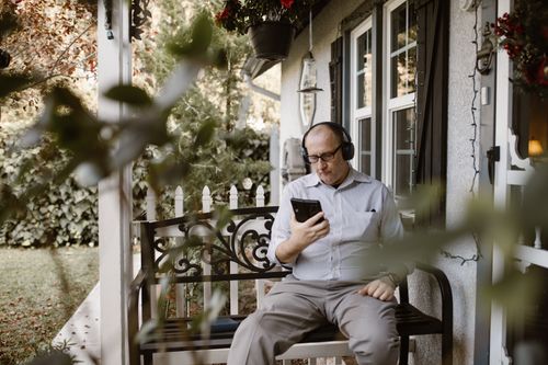 Free Senior man sitting outdoors, listening to music, and enjoying a peaceful moment with headphones. Stock Photo