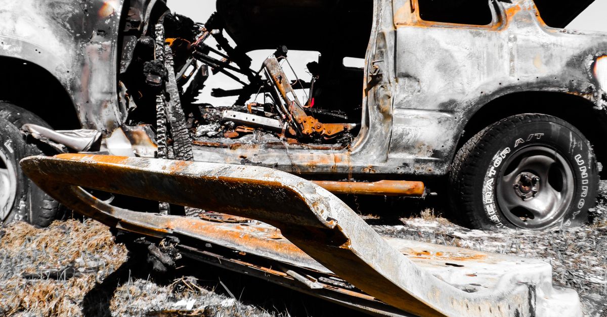 Close-up of a rusty, burnt-out vehicle wreck abandoned outdoors, offering a dramatic visual.