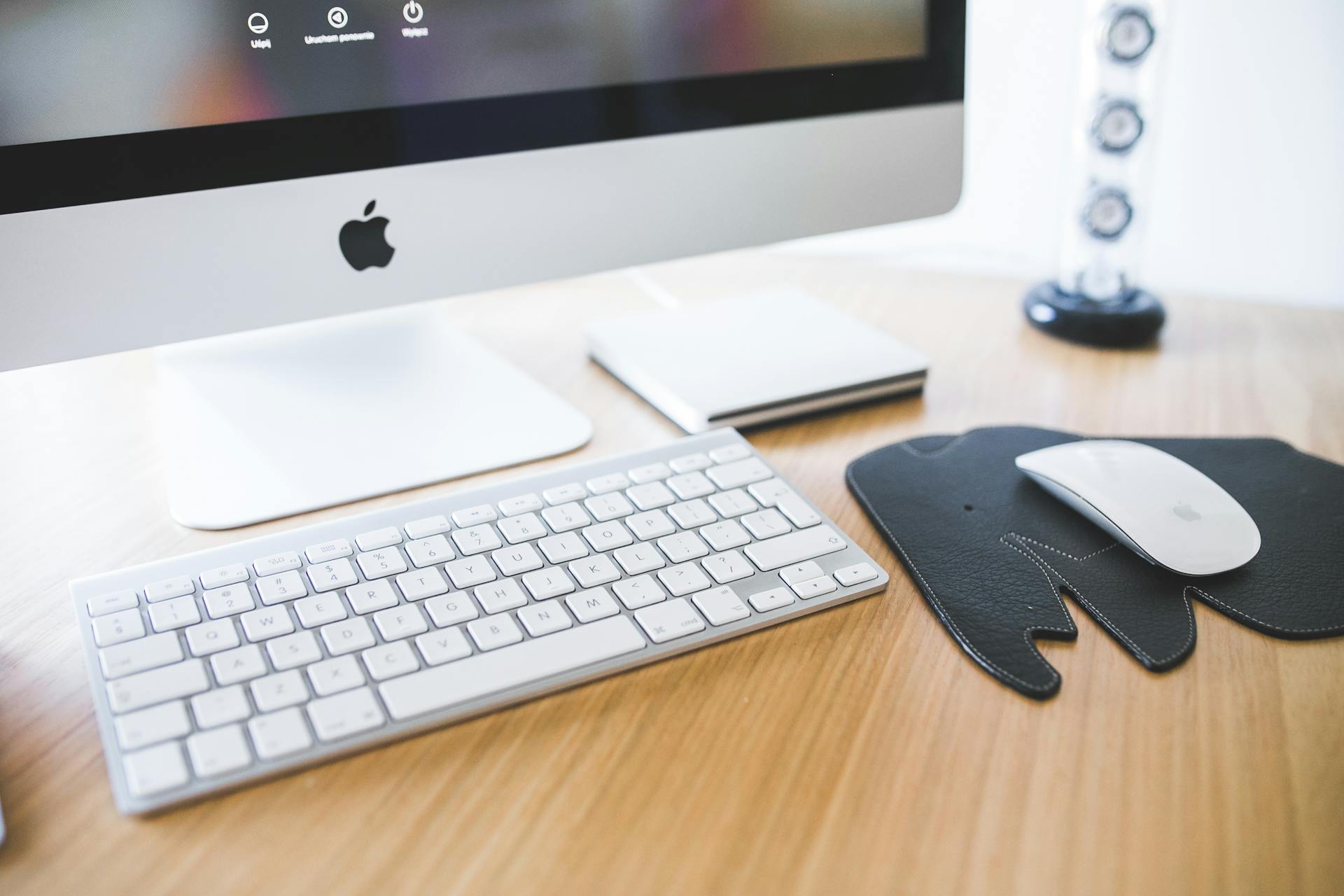 Sleek desktop setup featuring an iMac, keyboard, and mouse on a wooden desk for productivity.