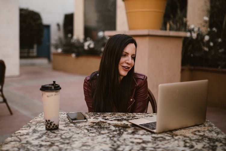 A Woman Sitting At The Table Using Laptop