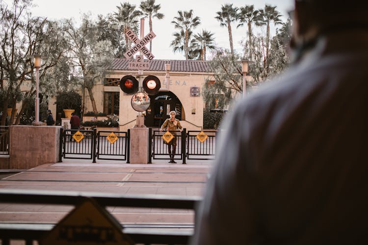 A Woman Standing Behind A Railway Gate