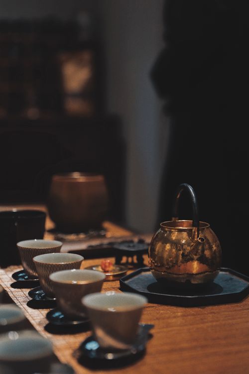 Free A classic still life of a teapot and cups arranged on a wooden table, evoking warmth and tradition. Stock Photo