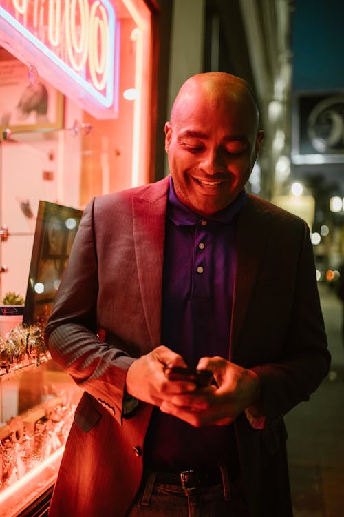 A Man Smiling while Using His Mobile Phone