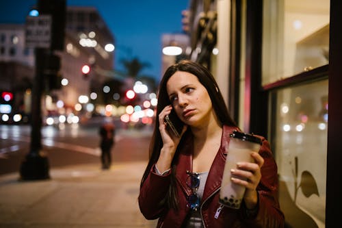 無料 透明なガラスのマグカップを保持している茶色の革のジャケットの女性 写真素材