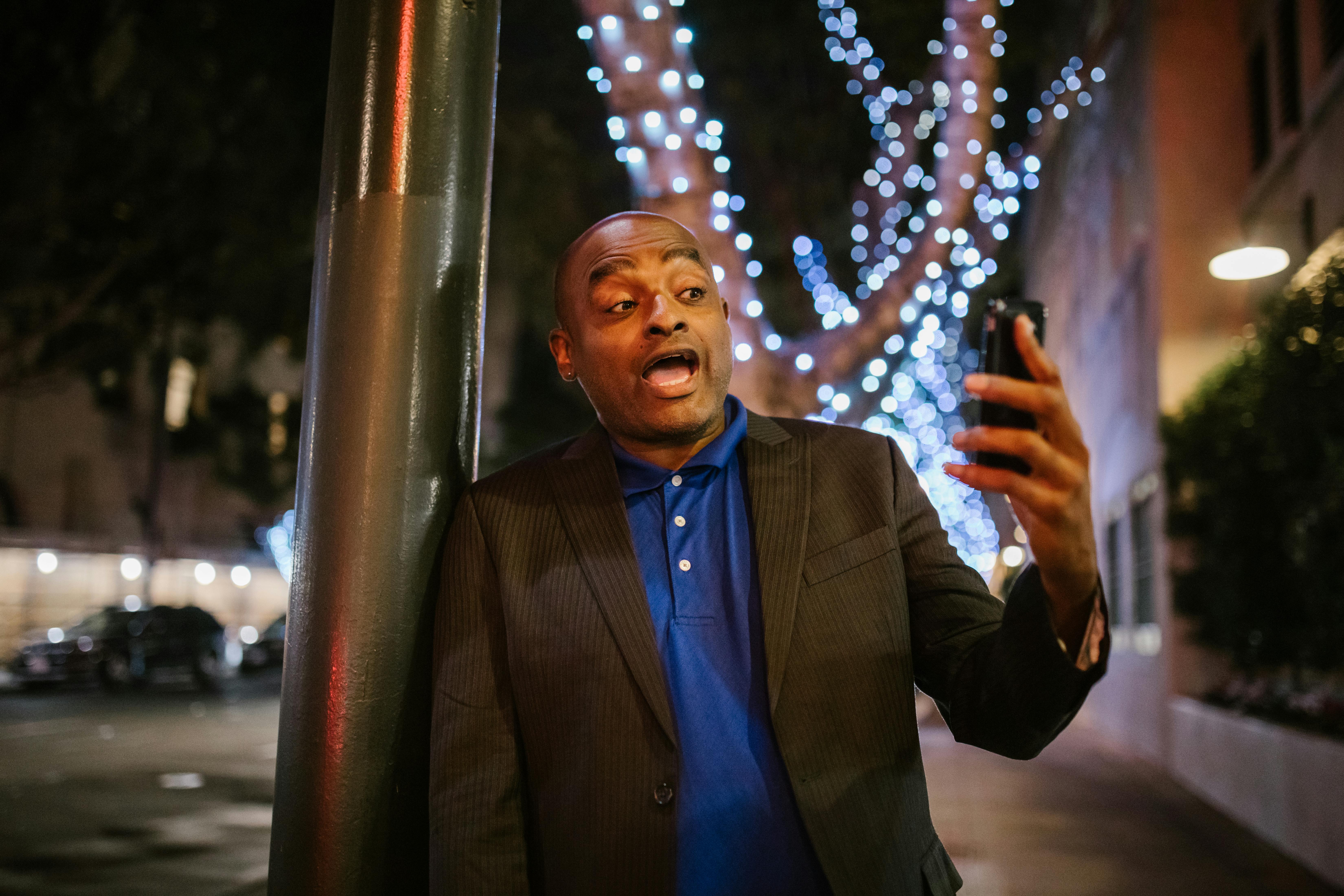 man holding a phone on a street at night