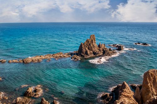 Free Stunning aerial view of rugged coastal rock formations surrounded by clear turquoise ocean waters. Stock Photo