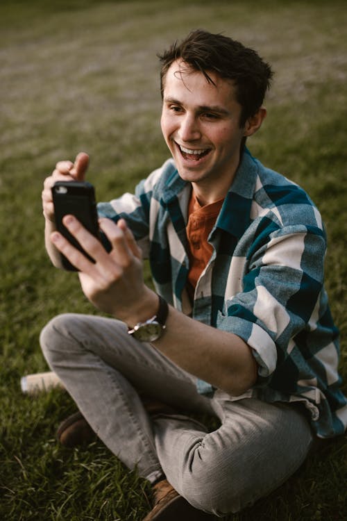 Man in Blue and White Checkered Button Up Shirt Holding Black Smartphone