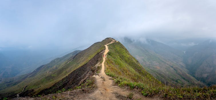 Hikers traverse a misty mountain ridge trail, showcasing breathtaking views.