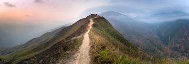 Distant hikers strolling on narrow footpath on hill