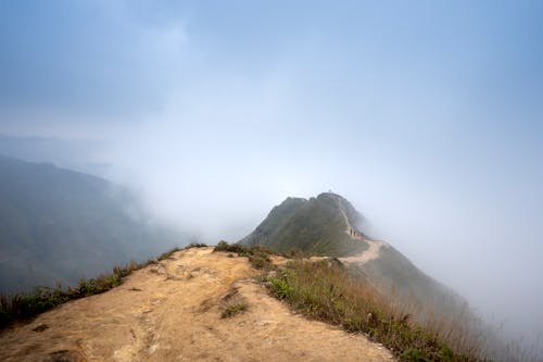 Distant hikers walking on trail in hazy mountainous terrain