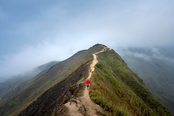 Walkers on a narrow path across a grassy hilltop, photo by Quang Nguyen Vinh on Pexels