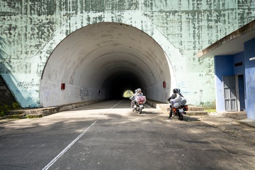 Anonymous people riding motorbikes near tunnel