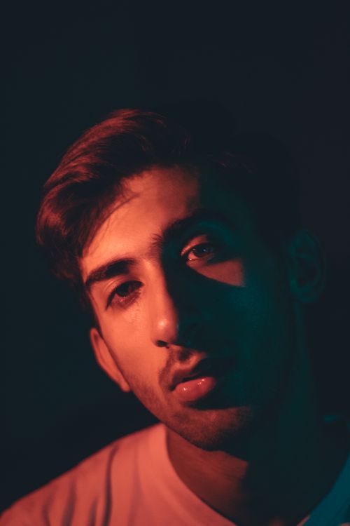 Free Artistic portrait of a young man with creative lighting effects, exuding a moody atmosphere. Stock Photo