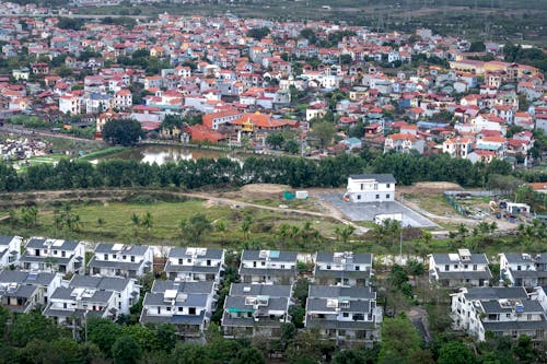 Drone view modern residential cottages located on grassy suburb district of modern town on summer day