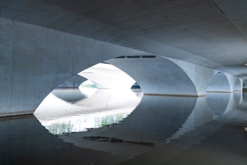 Area under white arched bridge reflecting in rippling calm river on sunny day