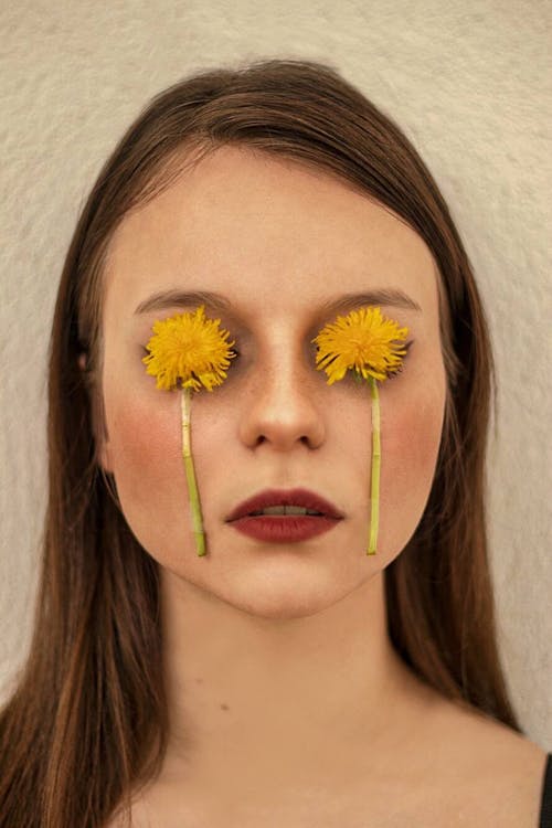 彼女の顔に黄色い花を持つ女性