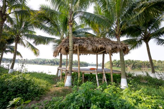 Wooden hut on grassy riverside in tropical park