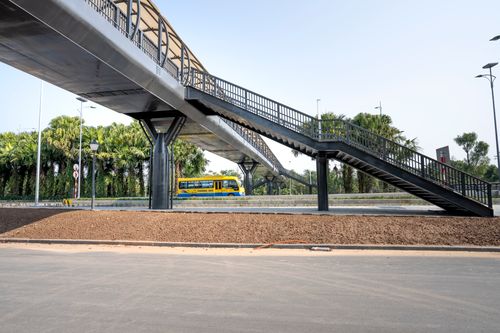 Free Fenced bridge with staircase above asphalt roadways against tropical trees under light sky in town Stock Photo