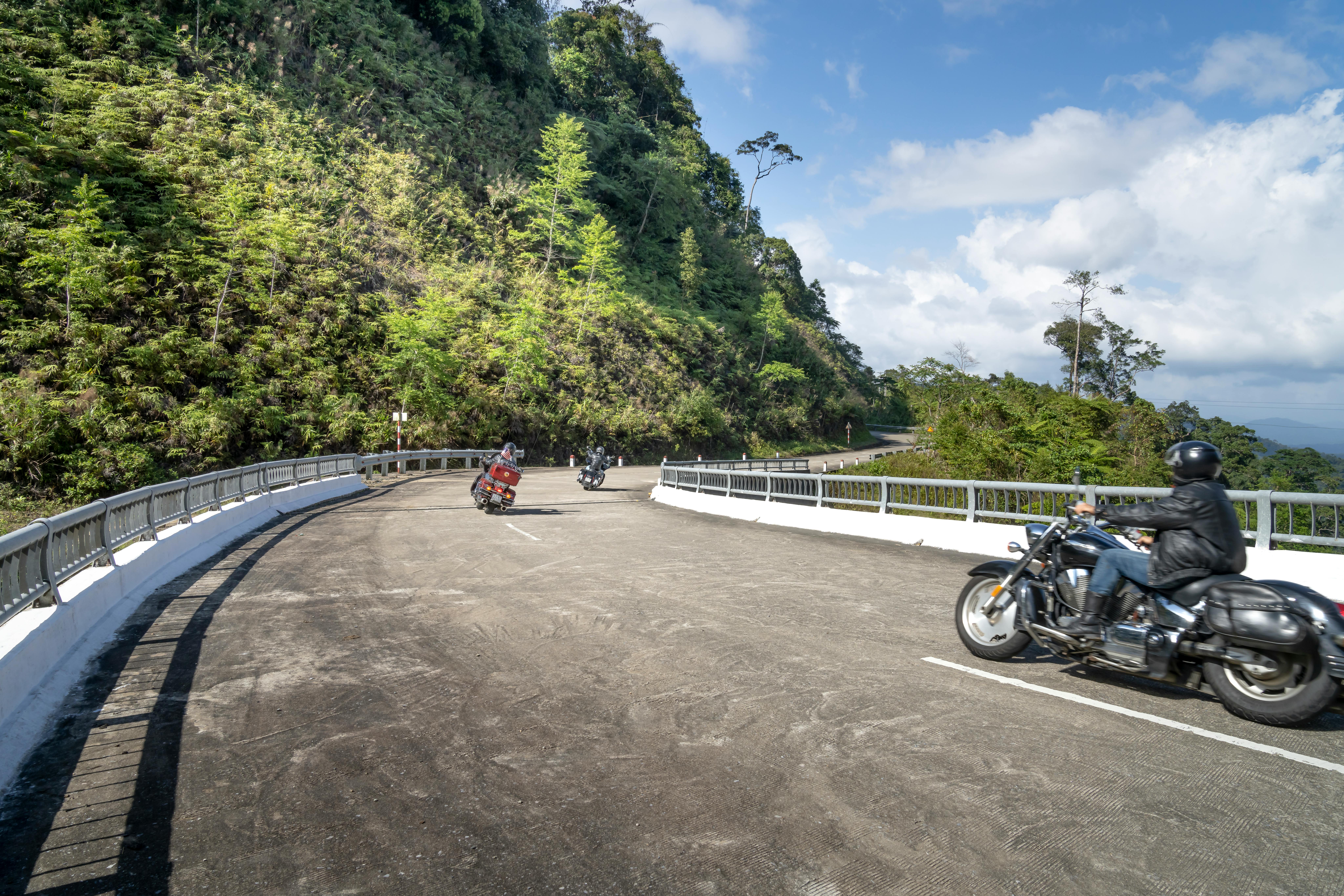 Anonymous motorcyclists driving bikes on wavy road in mountains ...