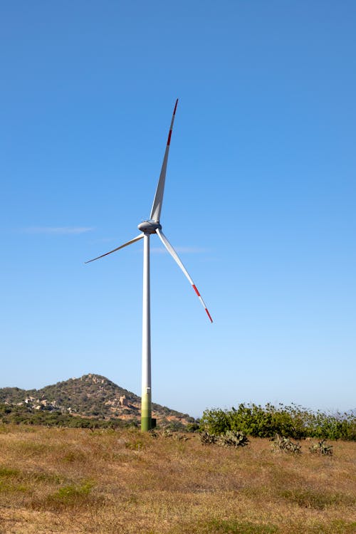Free Windmill on land against mount under blue sky Stock Photo