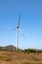 Windmill on land against mount under blue sky
