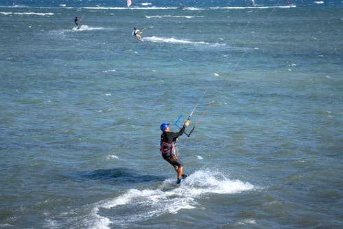 Anonymous kitesurfer riding in wavy sea on sunny day