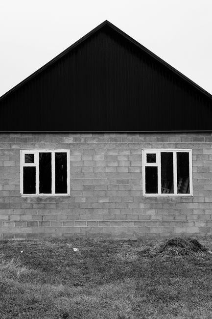 Monochrome image of a brick building facade with windows.