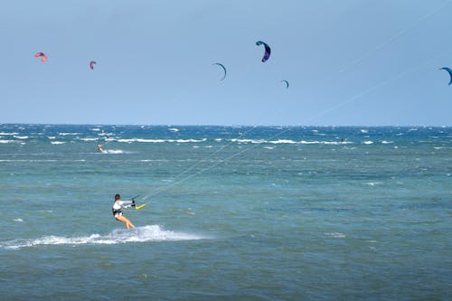 Anonymous lady practicing kitesurfing in ocean under blue sky